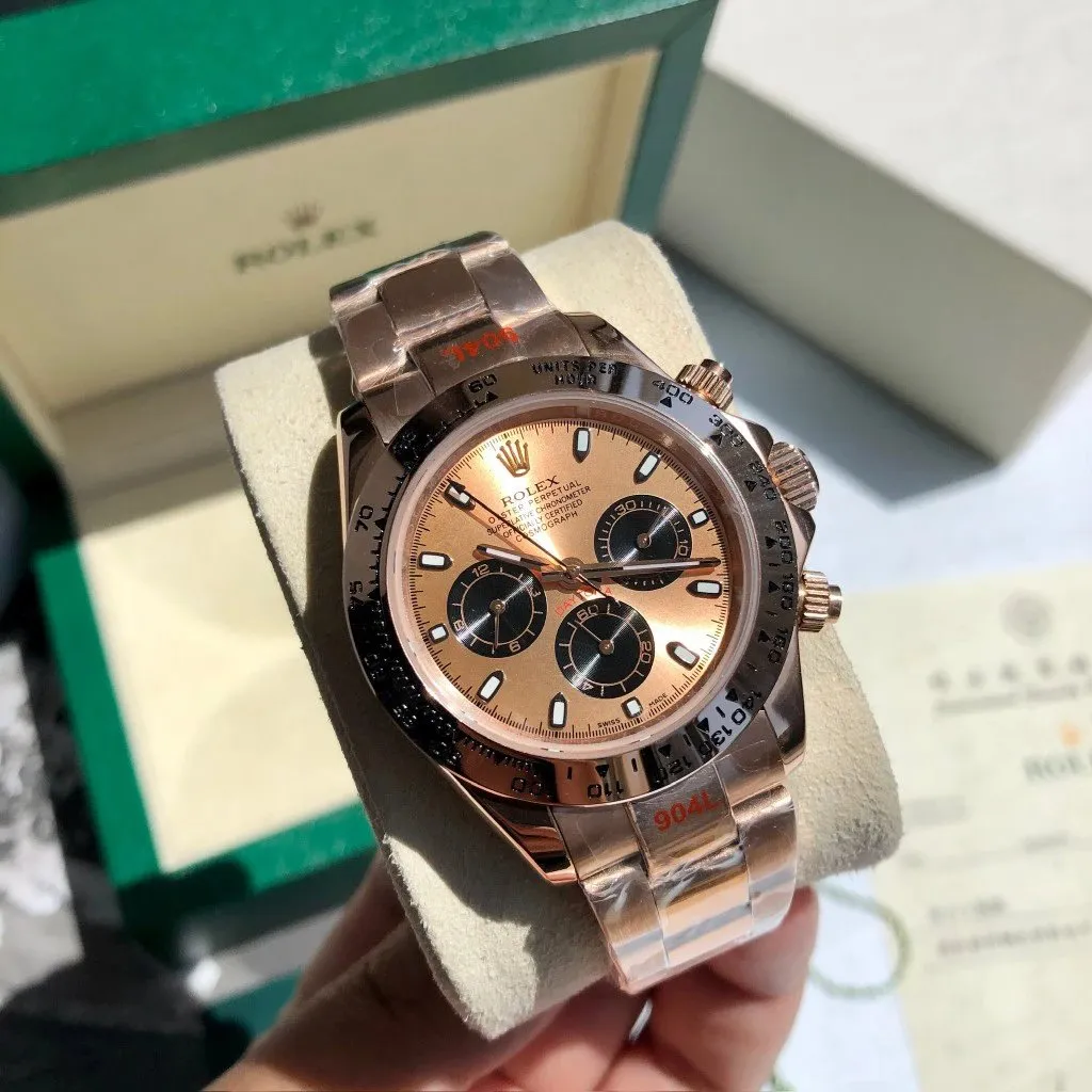 Rolex chronograph wristwatch with rose gold-tone bracelet, black dial, and branded box.