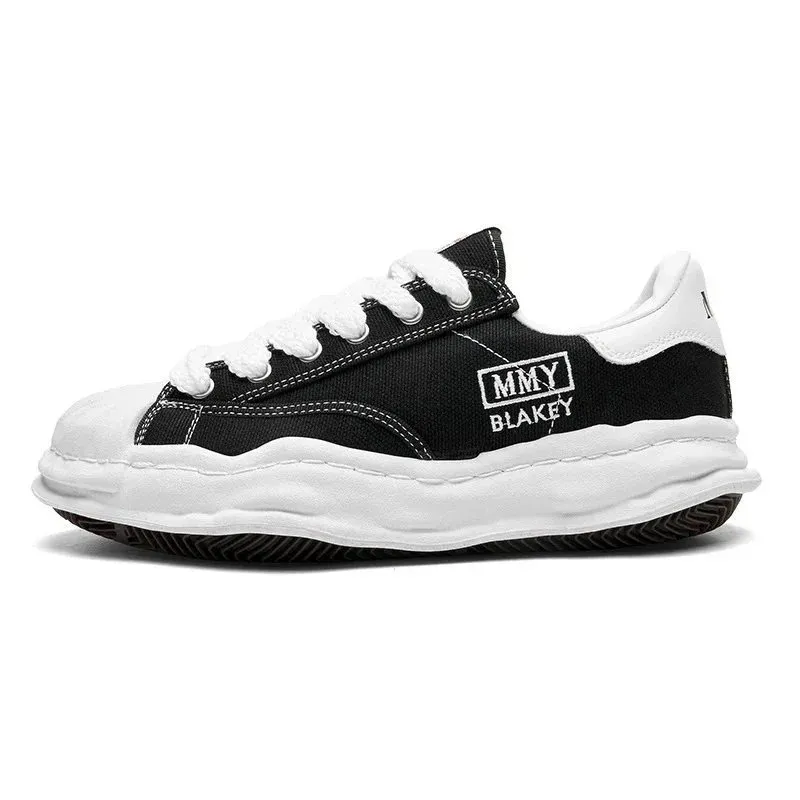 Black and white Alexander McQueen low-top sneaker with a thick sole and side logo patch.