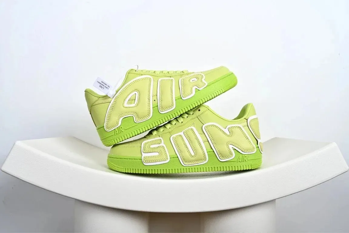 Nike sneakers w limonkowej zieleni z dużymi bocznymi napisami na studio zdjęciu.