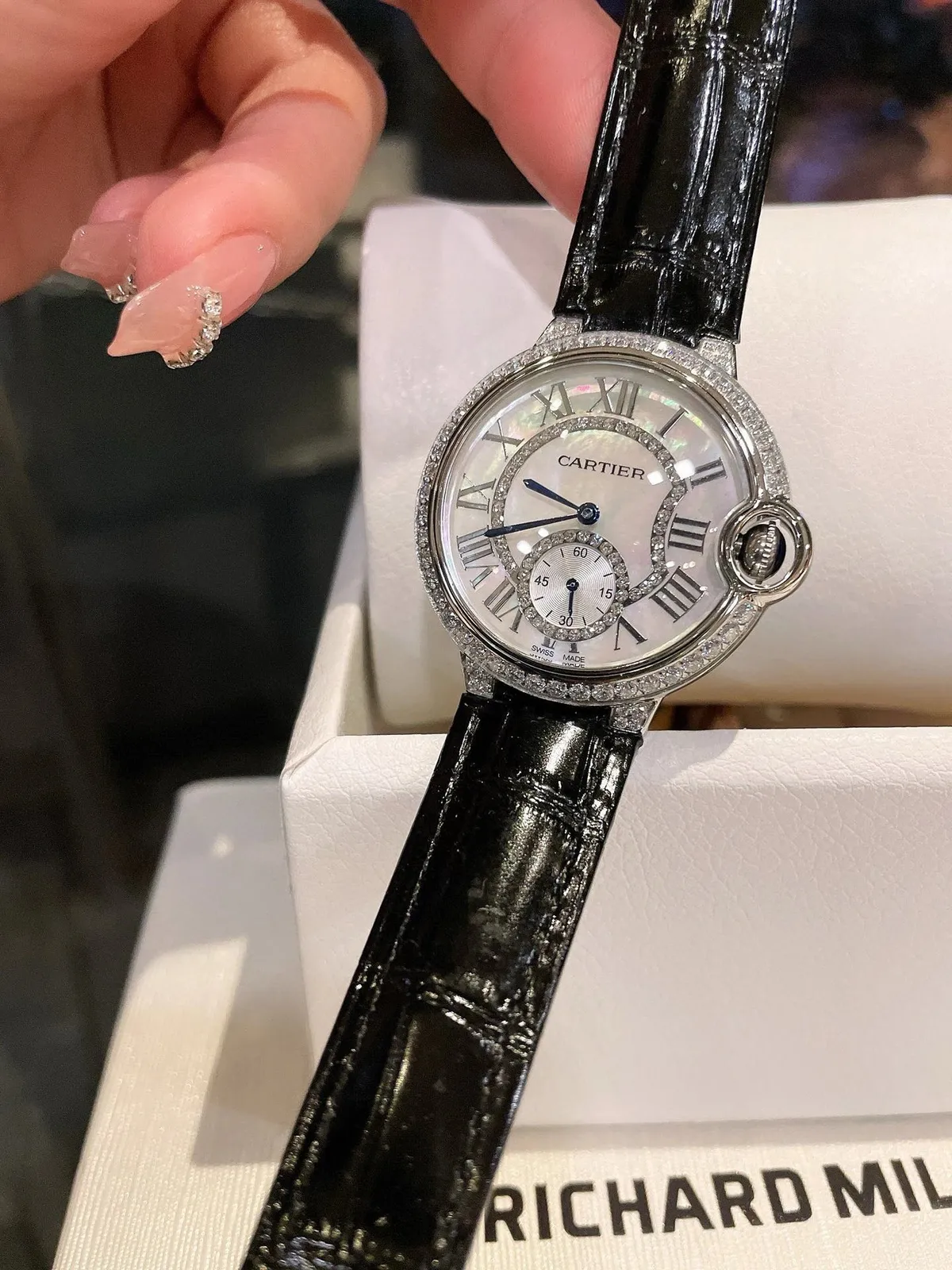 Cartier zegarek z kamienną lunetą, czarnym skórzanym paskiem i tarczą z rzymskimi indeksami.