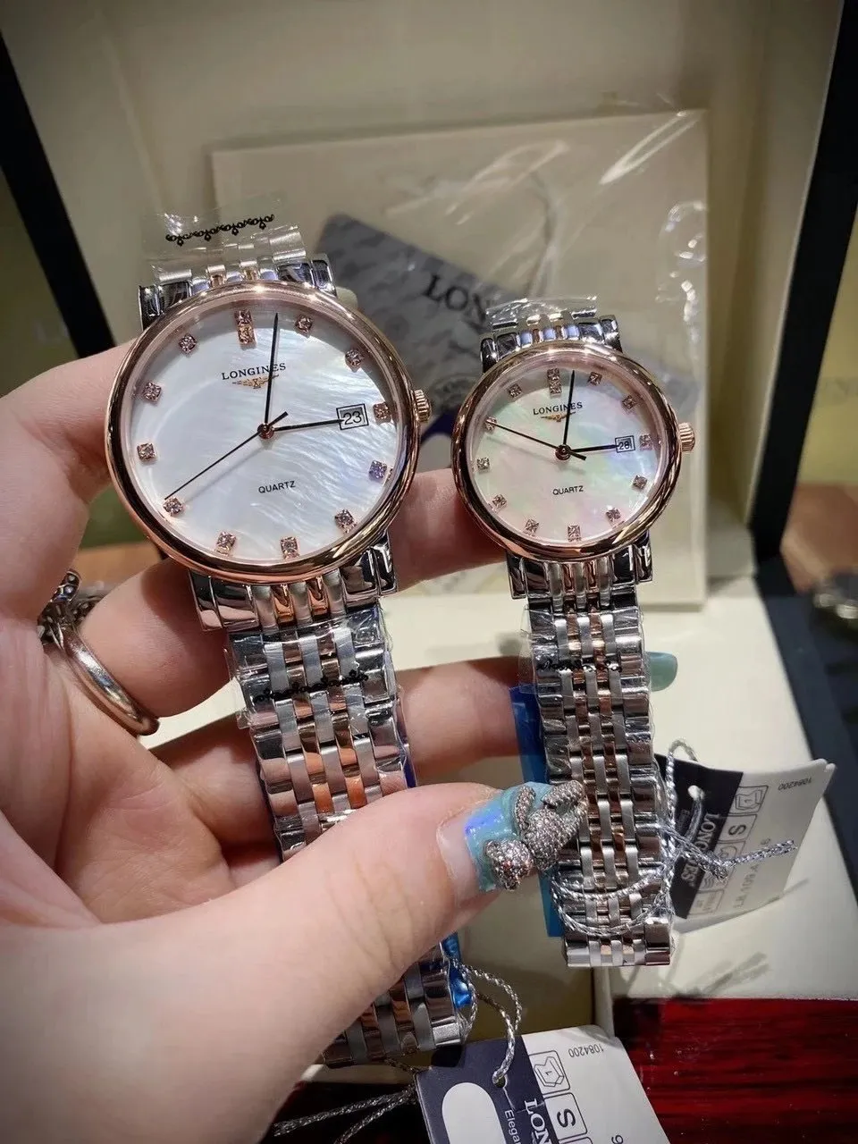 Dwa zegarki Longines z perłową tarczą i dwukolorową bransoletą w zbliżeniu.