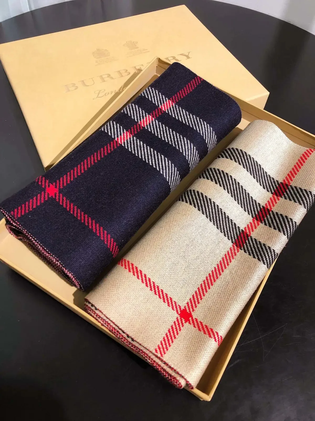 Burberry check pattern scarf folded in a branded box with navy, red, and beige checks.