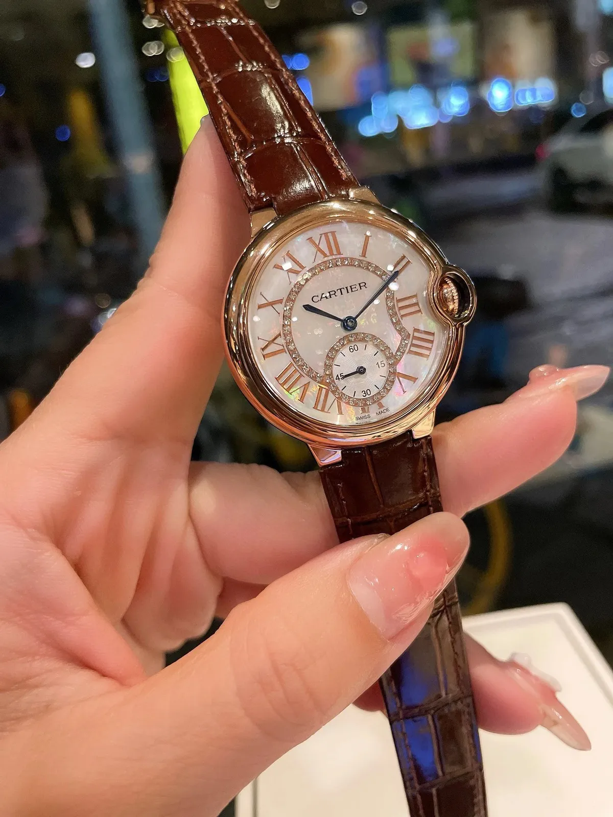 Cartier watch with mother-of-pearl dial, Roman numerals, and brown leather strap.