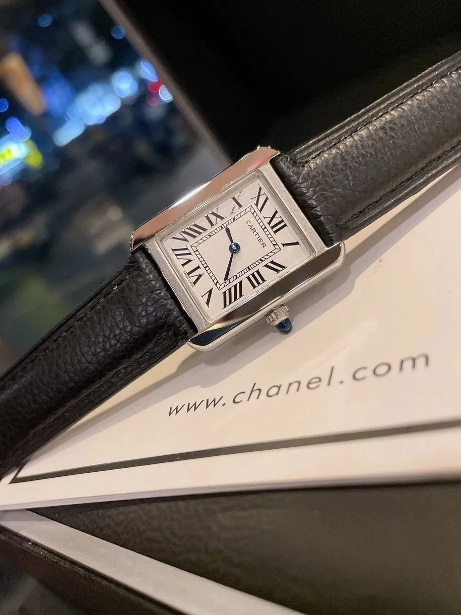 Cartier rectangular watch with a black leather strap, Roman numerals, and a blue crown.