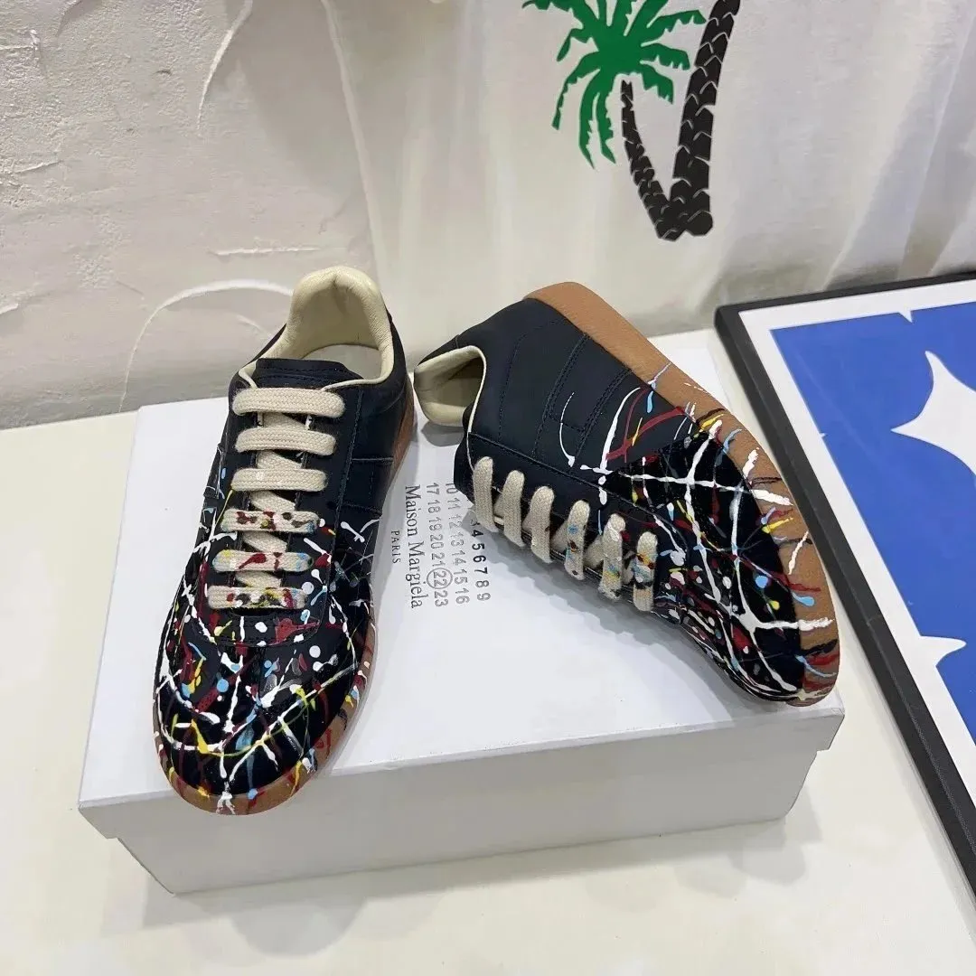 Maison Margiela low-top sneakers with paint-splatter accents and mismatched laces on a white box.
