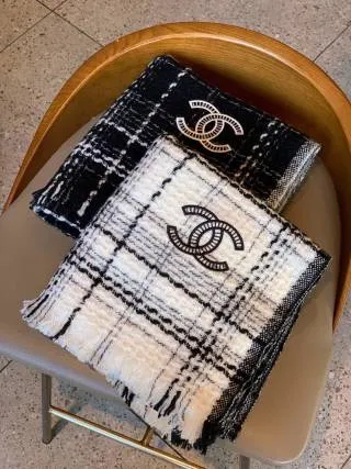 Chanel plaid tweed scarf with a centered CC-style logo patch and fringed edges.