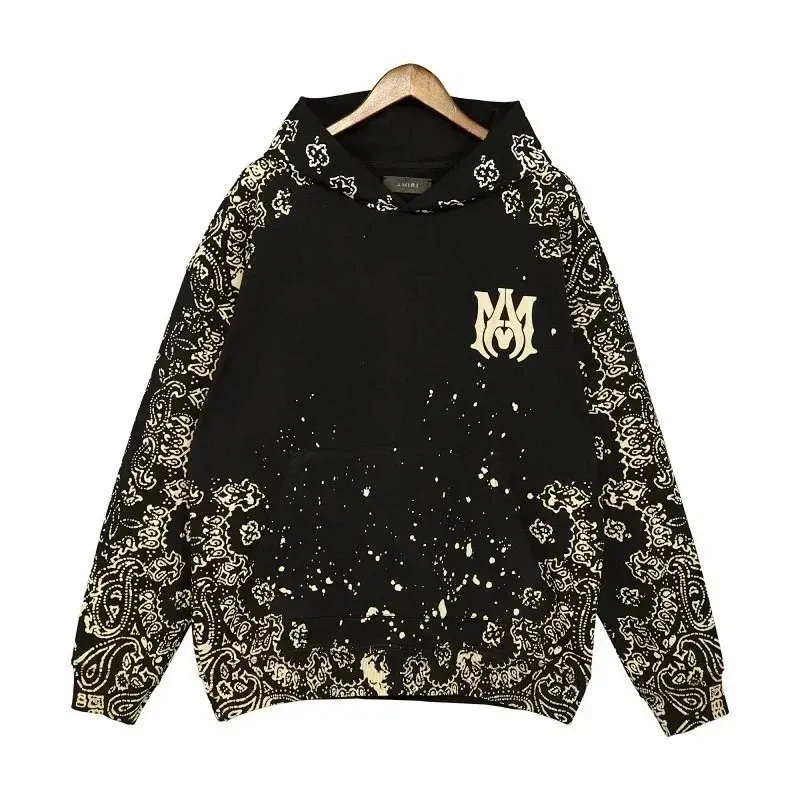 AMIRI hoodie with black base, paisley print, and small chest logo shown on a hanger.
