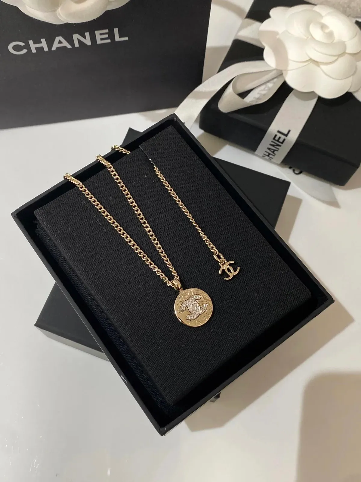Chanel gold-tone pendant necklace with a CC-style charm in a black presentation box.