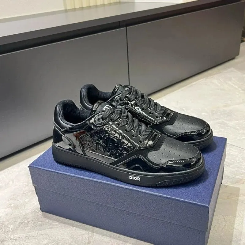 Czarne sneakersy Dior niski profil z logo na podeszwie, pokazane na niebieskim pudełku.