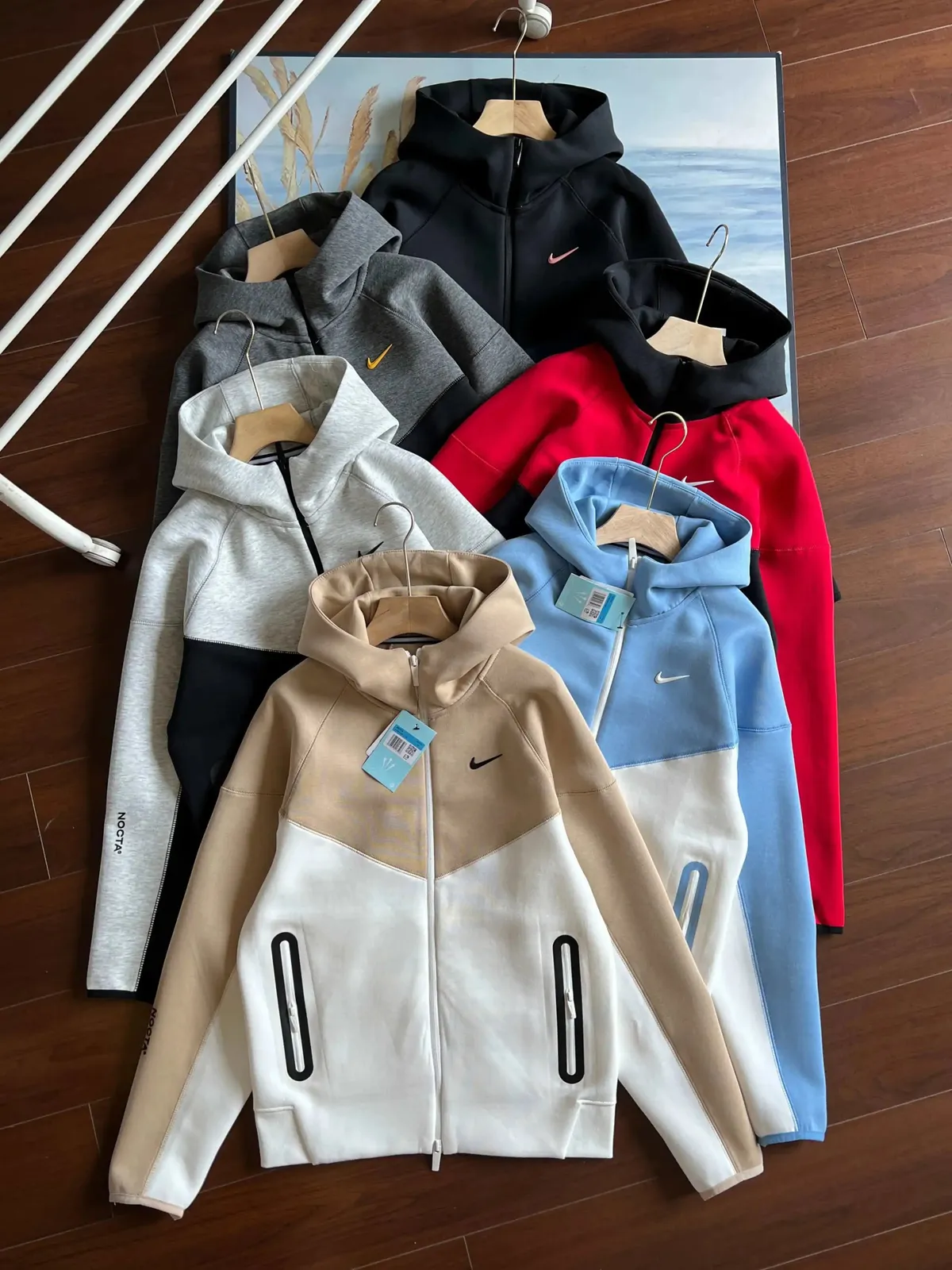 Nike hooded zip-up jackets laid flat in black, gray, beige, and other colorways with swoosh details.