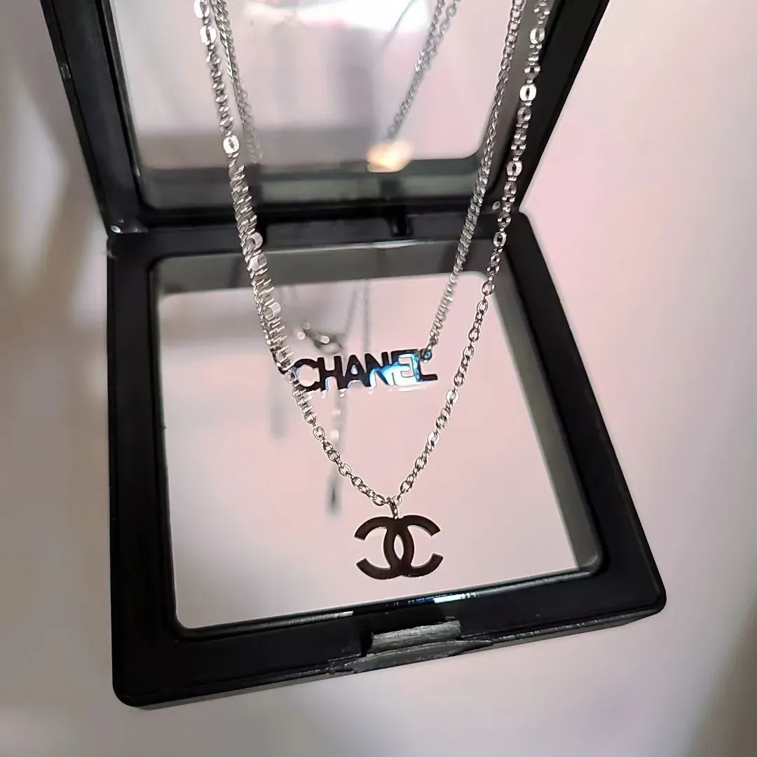 Chanel double-layer pendant necklace with silver-tone logo and CHANEL charms in a box.