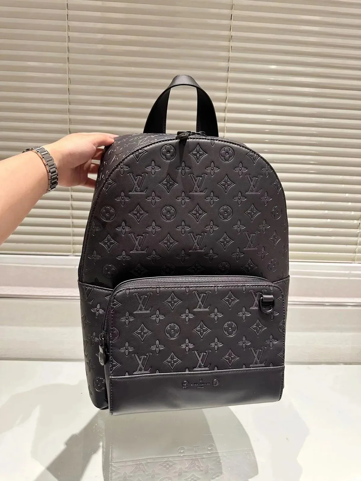 Black Louis Vuitton backpack with embossed monogram pattern and front zip pocket — alternate angle